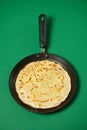 Crepe closeup, thin pancake on a frying pan, green background