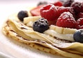 Crepe pancakes with banana and berries with sugar powder topping on white background.Macro.AI Generative Royalty Free Stock Photo