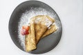 Crepe strawberry with powdered sugar on a black plate