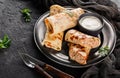 Crepes with chopped meat, greens and sour cream on black plate over dark background. Pancake week or Shrovetide. Healthy breakfast