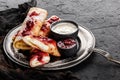 Crepes with cottage cheese, fruit jam, cherries, sour cream and icing sugar on black plate over dark background.Top view, flat lay Royalty Free Stock Photo