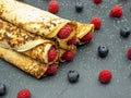 Crepes filled with jam and fresh raspberry and blueberries on slate