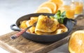 Crepes with Orange Sauce in a cast iron pan. Traditional French crepe Suzette with orange sauce. Royalty Free Stock Photo