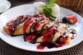 Crepes stuffed with fruit and covered with chocolate and berry syrups. Served with ice cream balls and strawberries. Thin pancakes Royalty Free Stock Photo