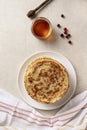 Crepes, thin pancakes with honey on a white plate. Marble background.