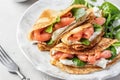 Crepes or thin pancakes with smoked salmon, soft cheese and spinach on a plate and fork close up. Pancake day Royalty Free Stock Photo