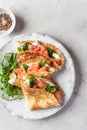 Crepes or thin pancakes with smoked salmon, soft cheese and spinach on a plate top view close up on gray textured Royalty Free Stock Photo