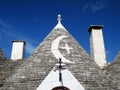 The "crescent with a cross" roof at the historical house "trullo" on Monte Pertica Street, Alberobello, ITALY