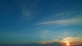 Crescent moon rising. Sweet orange cloud with purple shadow in blue sky. Sun halo is visible as cirrus clouds form in Royalty Free Stock Photo