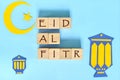 Crescent moon, star and lantern decoration with text on wooden blocks flat lay in blue background. Eid al fitr celebration Royalty Free Stock Photo