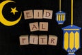 Crescent moon, star and lantern decoration with text on wooden blocks flat lay in dark black background. Eid al fitr celebration Royalty Free Stock Photo