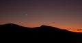 Crescent moon and sunset over silhouette of desert ridge on fall evening Royalty Free Stock Photo