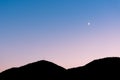 Crescent moon in sunset sky above sillhouette of mountains Royalty Free Stock Photo