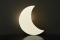 Crescent shaped glowing night lamp on black background