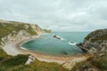 A crescent-shaped sea cove surrounded by a rocky coastline and beach on the Dorset coast in southern England