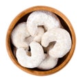 Crescent-shaped vanilla biscuits in wooden bowl over white