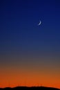 Cresent Moon On Horizon at Twilight Orange Glow Sunset Radio Towers Royalty Free Stock Photo