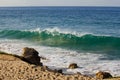 Cresting breaking wave on shoreline edge with washback foam on sandy shoreline