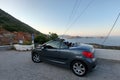 Crete. Greece - April 1, 2019: The girl and the cabriolet stand in front of a stunning panoramic view. Sea and winding mountain Royalty Free Stock Photo