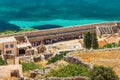 CRETE, GREECE - JULY 08 2023: Groups of tourist shelter from the sun in the shade from a large wall on the ancient fortress island