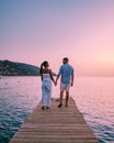 Crete Greece, young romantic couple in love is sitting and hugging on wooden pier at the beach in sunrise time with Royalty Free Stock Photo