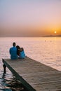 Crete Greece, young romantic couple in love is sitting and hugging on wooden pier at the beach in sunrise time with Royalty Free Stock Photo