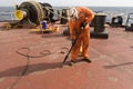 crew member of commercial cargo ship performing deck maintenance work
