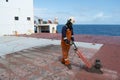 crew member of ship chipping the hatch cover surface with descaling machineg