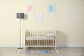 Crib and floor lamp near light wall in baby room Royalty Free Stock Photo