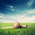 Cricket ball and bat on green grass with blue sky background - Ai Generated Royalty Free Stock Photo