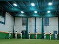 Cricket practice indoor club cricket lights on astrotruff men in white cricketers jogging inside the indoor stayindoors