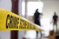 crime scene tape in building with blurred forensic team background