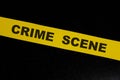 Crime scene yellow barricade tape warning and caution sign in dark black background.