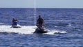 Two men ride jet skis on the sea