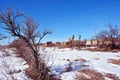 Crimean coquina rock blocks ruined farm walls, two water towers, dry weathered grass field covered with snow, elderberry bushes