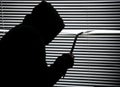 Criminal with crowbar is spying through the window. Old shutter blinds Royalty Free Stock Photo