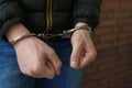 Criminal detained in handcuffs against wall