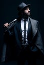 Criminal, fashion and man with bat for vintage, retro and Victorian gangster on dark background. Crime aesthetic