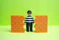 A criminal finds a hole in the wall. The concept of finding a vulnerability in security Royalty Free Stock Photo