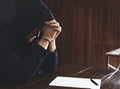 Criminal in handcuffs with confession at desk indoors