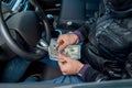 criminal man holding a large sum of dollar bills inside the car.