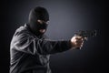 Criminal wearing black balaclava and hoodie with a gun