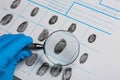 Criminalist studying fingerprints with magnifying glass