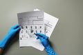 Criminologist exploring fingerprints with magnifier on grey