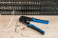 Crimper, utp Ethernet cable are on the background of internet switches. The pieces of the cable are next to the network