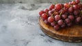 Crimson Beauty: Captivating Closeup of Red Grapes Situated on a Round Board on a Sleek Gray Surface