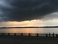 Crimson orange sunset on the river, dark clouds over the city`s waterfront