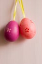 Crimson and pink hanged Easter eggs on striped background