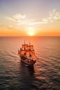 Crimson Tide. Small sailing ship in the open sea at sunset.