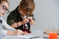 Cringe little boy looking through the microscope, girl taking notes next to him Royalty Free Stock Photo